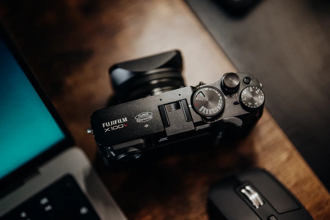 A camera and laptop on a wooden photography desk